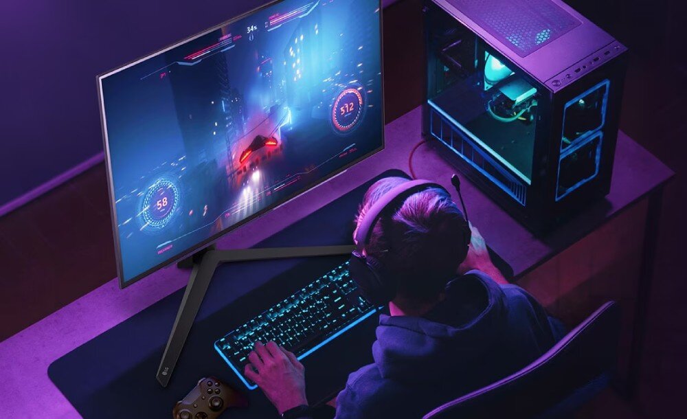 Monitor LG UltraGear 27GS95QE-B.AEU Gracz siedzący przy biurku z monitorem, klawiaturą mechaniczną i myszką. Na ekranie dynamiczna scena z wyścigówki, interfejs gry widoczny na ekranie, powłoka antyodblaskowa, widoczność, kąty widzenia