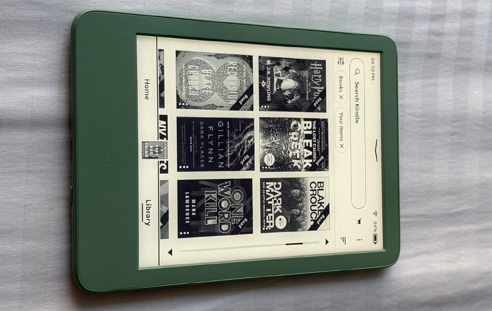 Zielony czytnik e-booków z wyświetlonym ekranem głównym, na którym widoczne są okładki książek i menu z opcjami \'Home\' i \'Library\'.