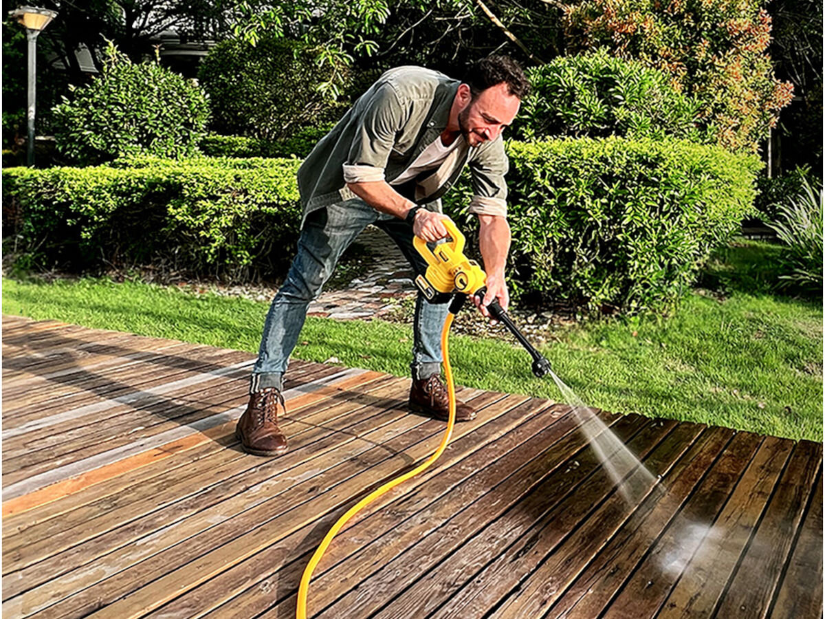 Myjka ciśnieniowa IMOU GYQXJ, ogród, meble, kostka, powierzchnie, w tle ogród, mężczyzna schylając się myje taras drewniany myjką ciśnieniową