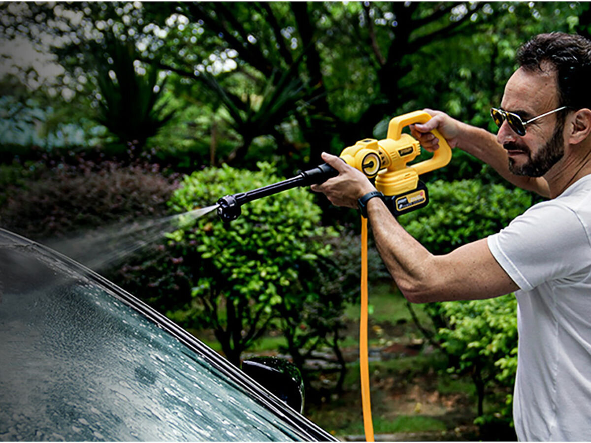 Myjka ciśnieniowa IMOU GYQXJ, otoczenie, auto, taras, porządek, mężczyzna spryskuje przednią szybę auta myjką ciśnieniową