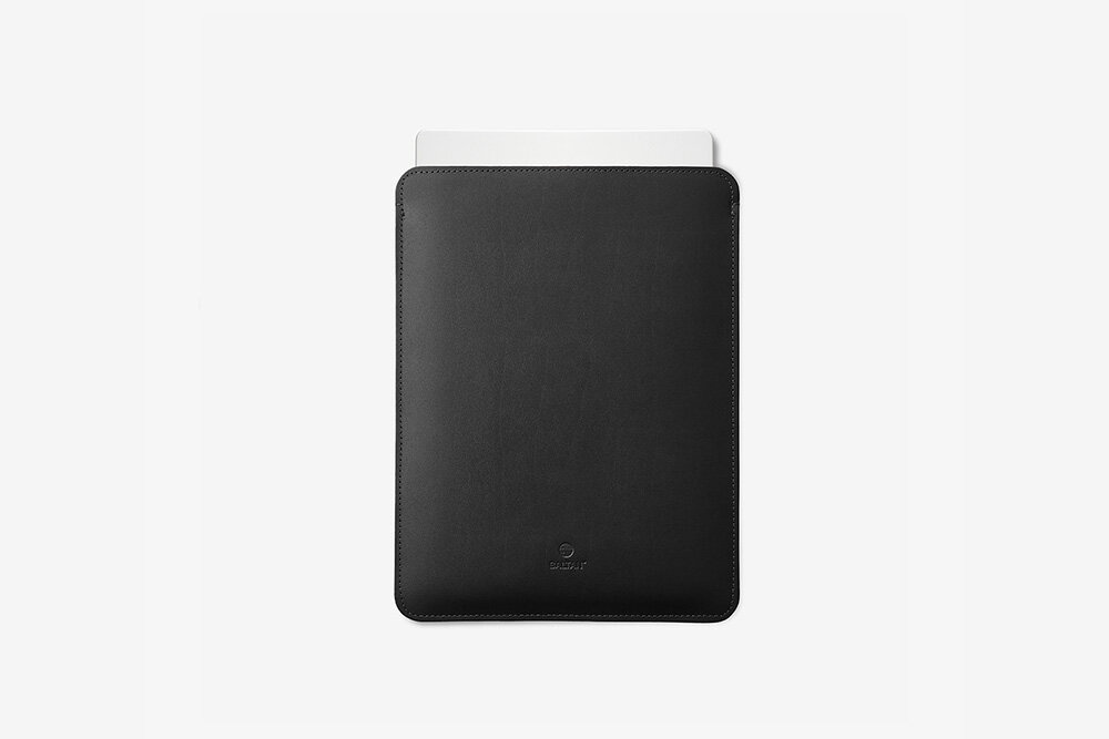 Etui na laptopa BALTAN Sleeve do Apple MacBook Air M4 15.3 cali Czarny skóra naturalna wytrzymałość ochrona Czarne skórzane etui na laptopa widziane z przodu, z częściowo wysuniętym laptopem u góry na białym tle.