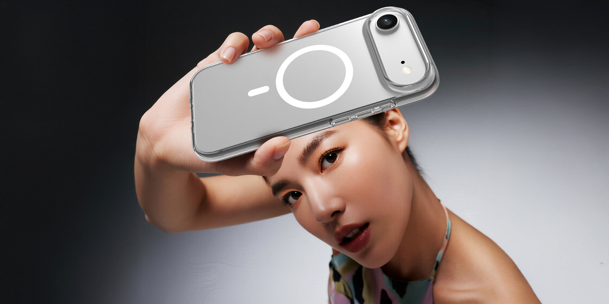 Zbliżenie na tył smartfona w etui z pierścieniem magnetycznym, obok widoczna ładowarka MagSafe podczas bezprzewodowego ładowania