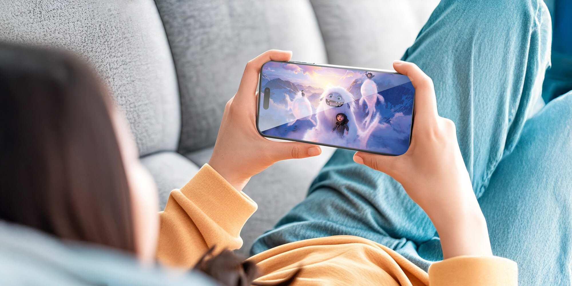 Osoba trzymająca smartfon w dłoniach i oglądająca animowany film na ekranie zabezpieczonym szkłem ochronnym