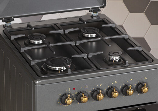 Zbliżenie na płytę gazową ze złotymi pokrętłami.