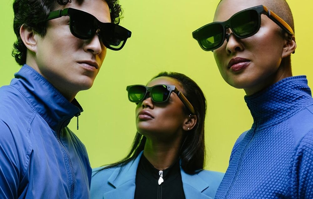 Trzy osoby noszące okulary przeciwsłoneczne na tle w odcieniach zieleni i żółci. Osoby mają na sobie niebieskie ubrania.