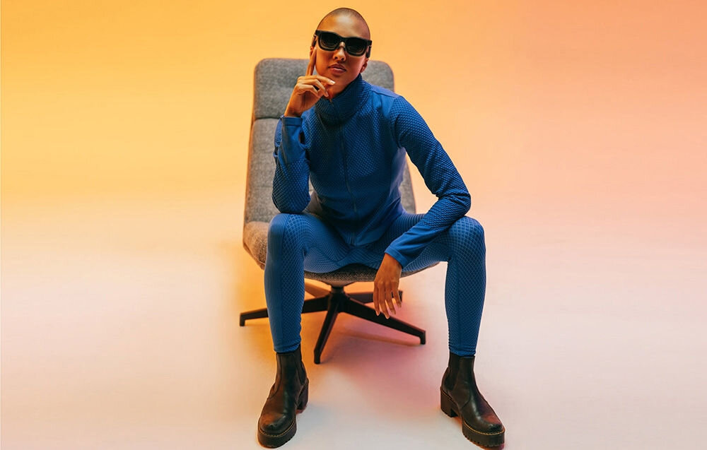 Okulary VITURE XR Luma Czarny Kobieta w granatowym ubraniu siedzi na krześle w okularach VR regulowane elementy miękkie noski trzy rozmiary wygoda niezależnie od kształtu twarzy odporne na intensywne użytkowanie