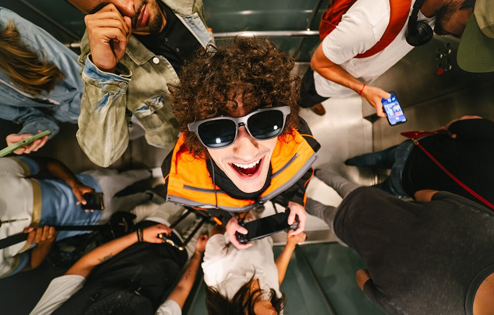 Okulary VITURE XR Luma Czarny chłopak z założonymi okularami wśród tłumu ludzi zaawansowane rozwiązania technologiczne półprzezroczysta konstrukcja waga ergonomicznie zaprojektowane dopasowują się do twarzy