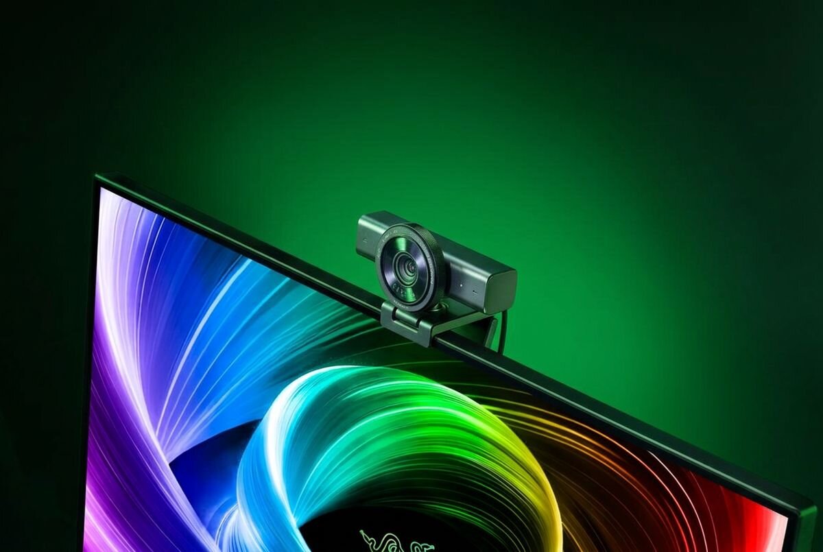 RAZER Kiyo V2 4K - Kamera zamontowana na górnej krawędzi monitora ze świecącym tapetą RGB w tle