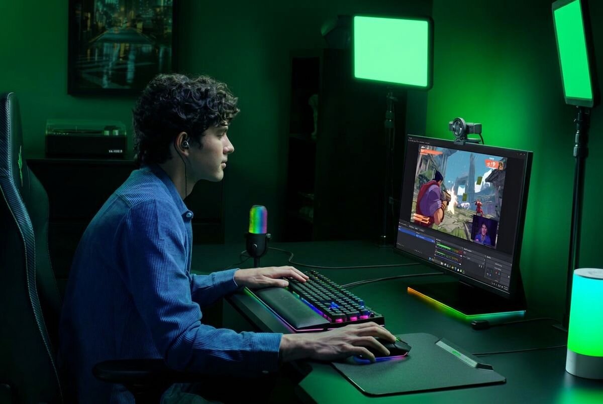 RAZER Kiyo V2 4K Razer Kiyo V2 kamera internetowa 4K matryca Sony STARVIS™ 4K przy 30 FPS - Stanowisko do streamingu z graczem siedzącym przy biurku i kamerą zamontowaną na monitorze