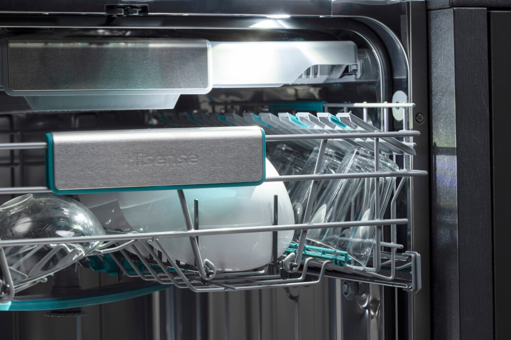 ZMYWARKA HISENSE HS693A90XAD Wysunięty górny kosz zmywarki Hisense jest wypełniony szklankami i białymi naczyniami ustawionymi w rzędach. Na środku kosza znajduje się podłużna listwa w kolorze stali szczotkowanej z logo Hisense, a nad nią widać wewnętrzne oświetlenie komory oświetlenie led wnętrze zmywarki komfort załadunku