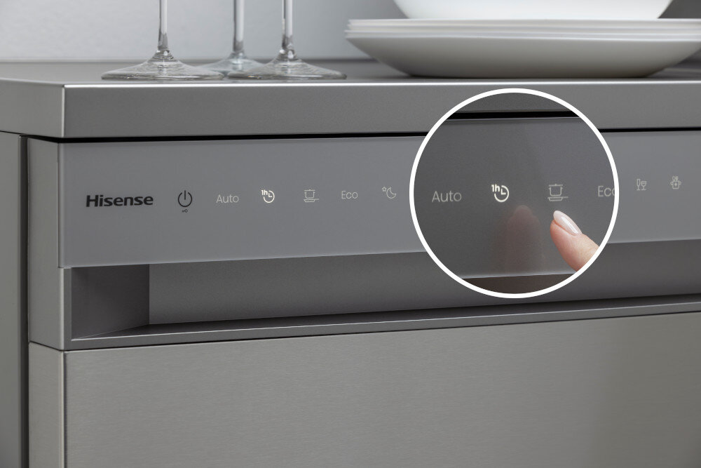ZMYWARKA HISENSE HS693A90XAD Zbliżenie na panel dotykowy zmywarki Hisense przedstawia palec wybierający szybki program oznaczony ikoną „1h” w podświetlonym, okrągłym zbliżeniu. Na szarym froncie widoczne są także inne symbole programów, w tym Auto, Eco i tryb intensywny program 60 minut szybkie mycie 65 stopni