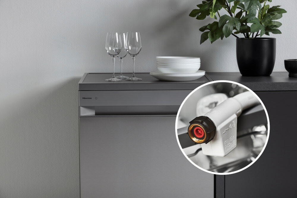 ZMYWARKA HISENSE HS693A90XAD Zmywarka wolnostojąca Hisense stoi przy ciemnym blacie kuchennym, na którym ustawiono kieliszki, talerze i doniczkę z rośliną. W prawym dolnym rogu dodano powiększone kółko z przyłączem AquaStop w wężu dopływowym, pokazujące zabezpieczenie przed zalaniem aqua protect zabezpieczenie przed zalaniem bezpieczeństwo