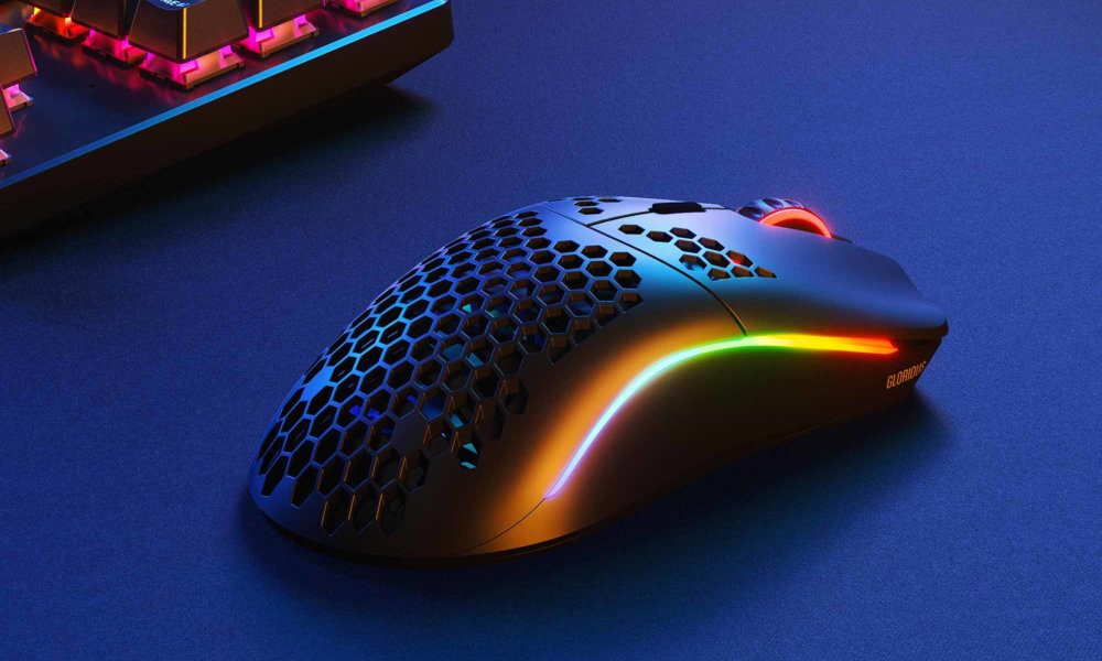 GLORIOUS PC Model O Wireless Tryb Tryb 2.4 GHz z odbiornikiem USB-A niską latencję szybką reakcję i wysoką precyzję USB-C jednoczesnego ładowania i pracy przewodowej - mysz z podświetleniem na ciemnym biurku obok klawiatury