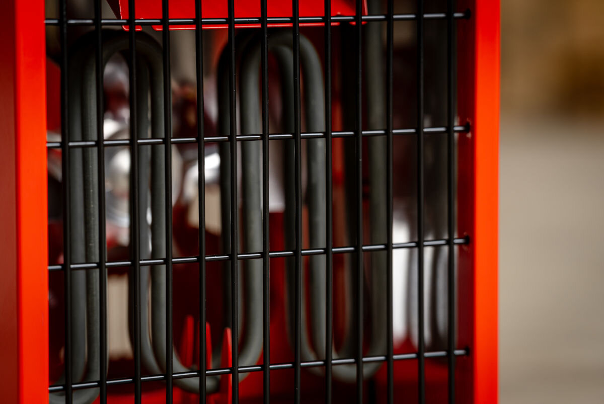 Nagrzewnica elektryczna DEDRA DED9920, przegrzanie, IP24, ochrona, wilgoć, Widok nagrzewnicy DED9920 ustawionej na białej podłodze garażu, działająca, widoczny żar.