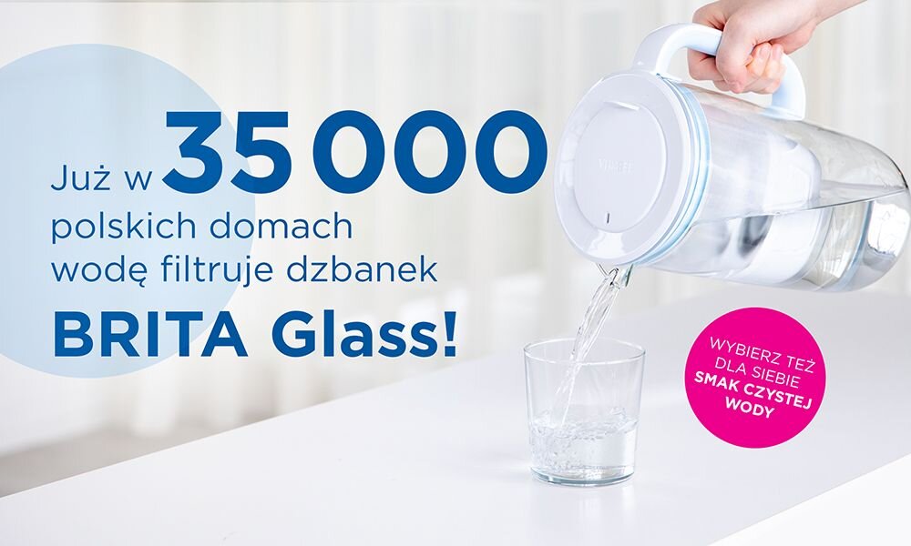 Osoba nalewa wodę z dzbanka do szklanki. Tekst na obrazie: \'Już w 35 000 polskich domach wodę filtruje dzbanek BRITA Glass!\' oraz \'WYBIERZ TEŻ DLA SIEBIE SMAK CZYSTEJ WODY\'.