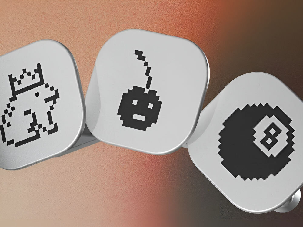 Odznaki LEDGER Nano Gen5 Pakiet Odznak 3 Zbliżenie na trzy małe, kwadratowe żetony lub przyciski Ledger Nano, ułożone w rzędzie, na rozmytym tle w odcieniach brązu, pomarańczu i różu. Na żetonach widnieją czarne, pikselowe ikony: z lewej strony postać w koronie (być może królik lub maskotka), pośrodku bomba z lontem (z twarzą), a z prawej czarna bila bilardowa z numerem 8.