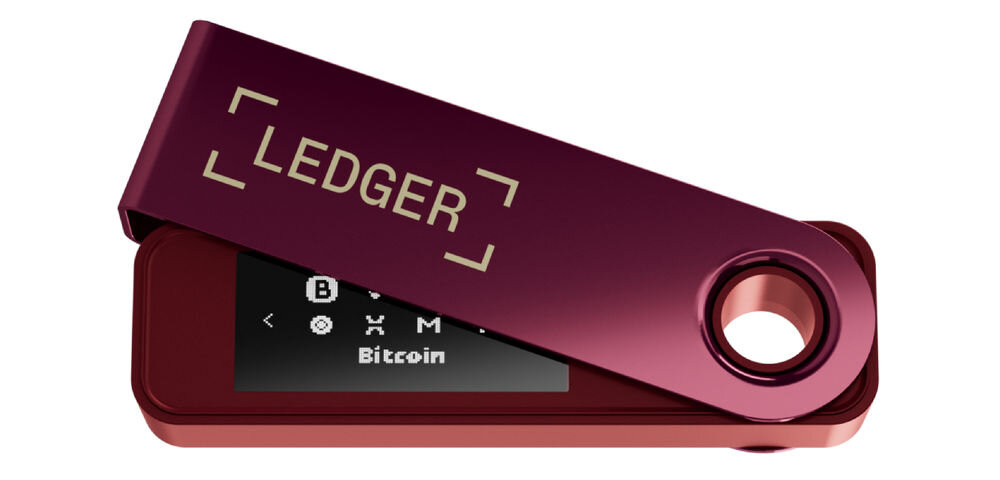 Portfel kryptowalut LEDGER Nano S Plus Sprzętowy portfel kryptowalutowy Ledger Nano S Plus w kolorze bordowym, z metalową osłoną częściowo odsuniętą, ukazującą wyświetlacz z ikonami kryptowalut i napisem Bitcoin. Na osłonie widoczne logo LEDGER. Widok pod kątem.