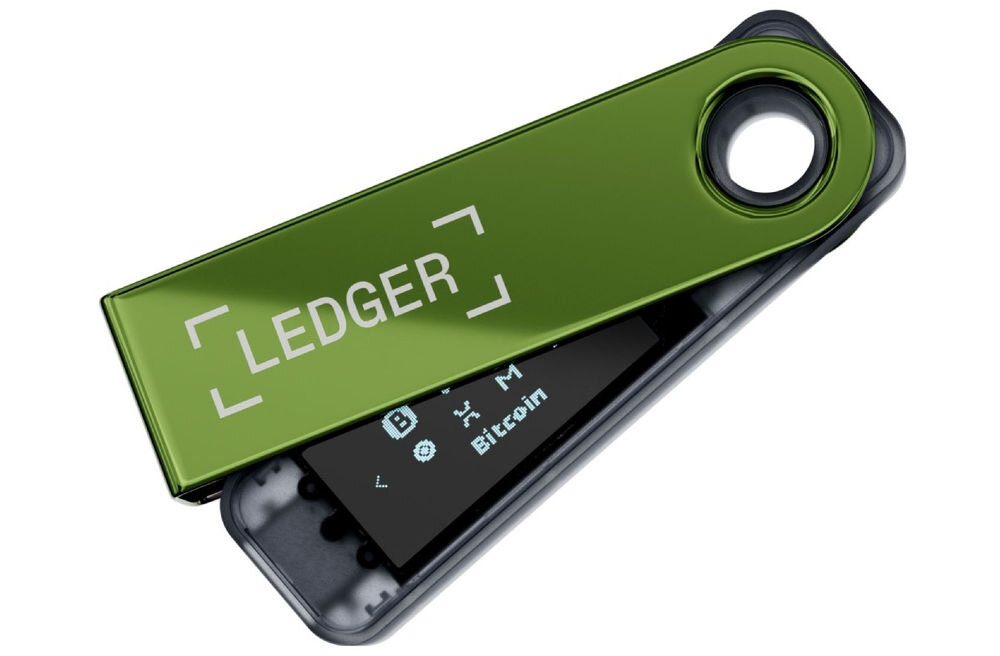 Portfel kryptowalut LEDGER Nano S Plus Sprzętowy portfel kryptowalutowy Ledger Nano S Plus w kolorze zielono-szarym, z metalową osłoną częściowo odsuniętą, ukazującą wyświetlacz z ikonami kryptowalut i napisem Bitcoin. Na osłonie widoczne logo LEDGER.