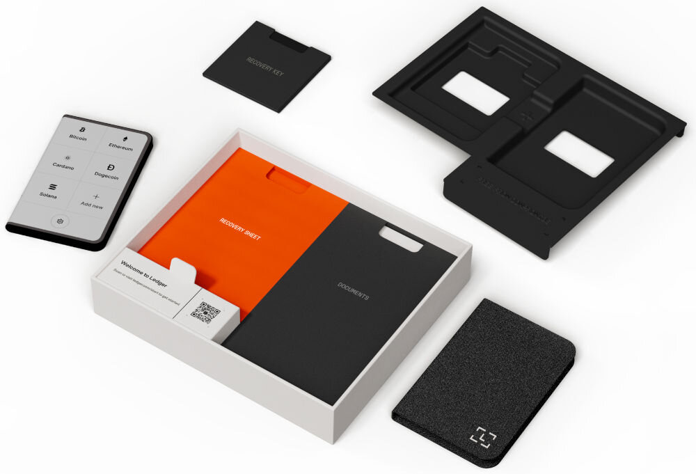 Portfel kryptowalut LEDGER Stax Crypto Hardware Wallet + Klucz odzyskiwania Zawartość opakowania zestawu Ledger Stax rozłożona na białym tle. Zawiera: portfel sprzętowy Ledger Stax (z wyświetlonym menu), otwarte białe pudełko z pomarańczowym i czarnym folderem na dokumenty (RECOVERY SHEET, DOCUMENTS), czarną kartę RECOVERY KEY, górną część opakowania oraz czarne, teksturowane etui na urządzenie.