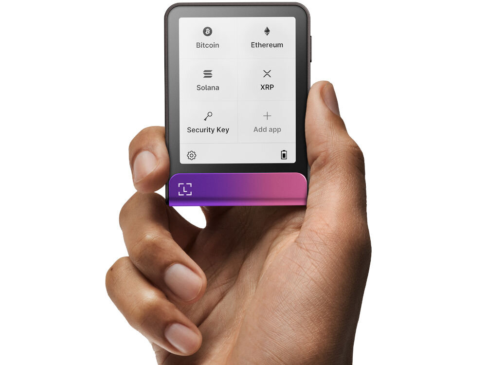 Portfel kryptowalut LEDGER Flex Ledger Stax stoi na drewnianym blacie obok szklanego kubka z kawą i pęku kluczy. Na ekranie urządzenia widnieje komunikat: Restored successfully from your backup (Pomyślnie przywrócono z kopii zapasowej) z opcją Tap to continue (Dotknij, aby kontynuować). Obok leży Ledger Recover Card.