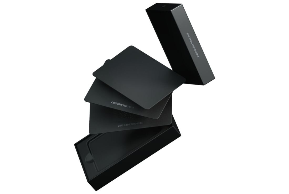 Karty Tangem wysuwają się z białego pudełka zestawu zaprezentowane w dynamicznym, unoszącym się układzie - Certyfikat EAL6+ i IP68 