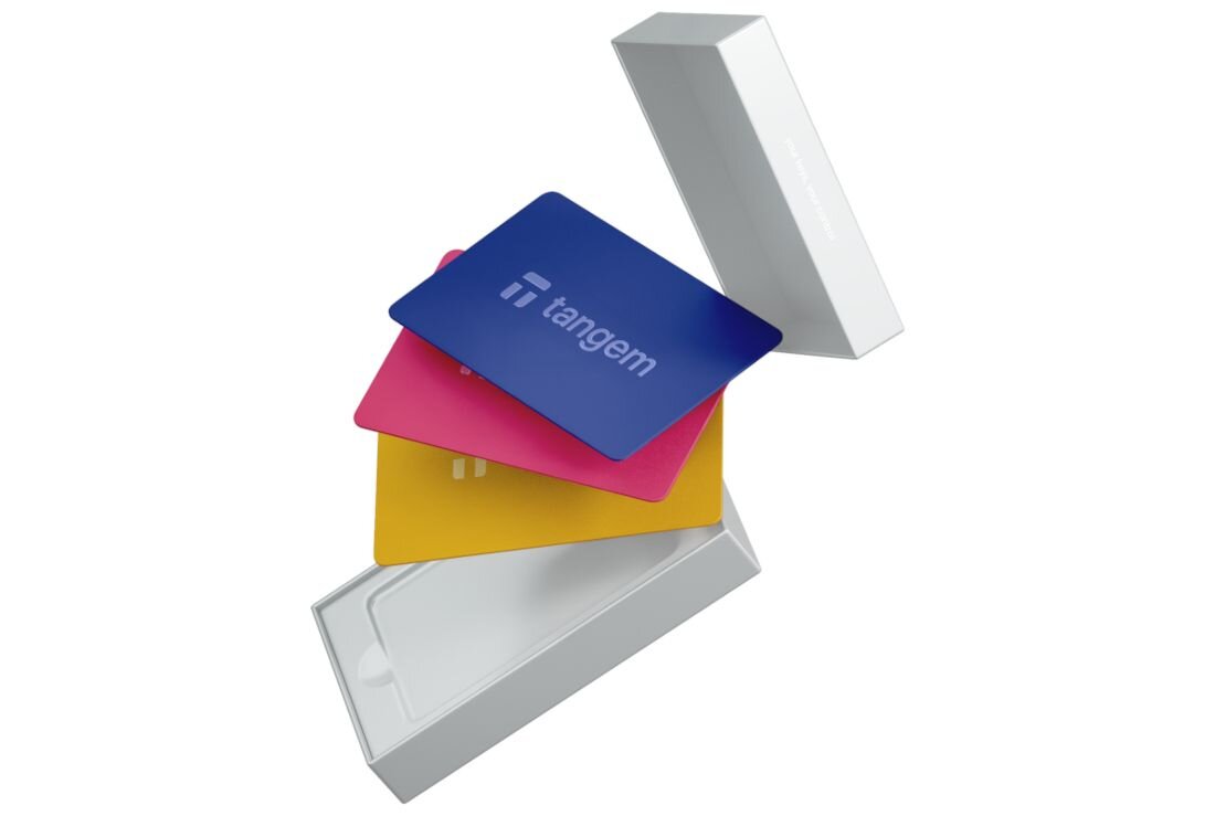 Karty Tangem wysuwają się z białego pudełka zestawu zaprezentowane w dynamicznym, unoszącym się układzie - Certyfikat EAL6+ i IP68 