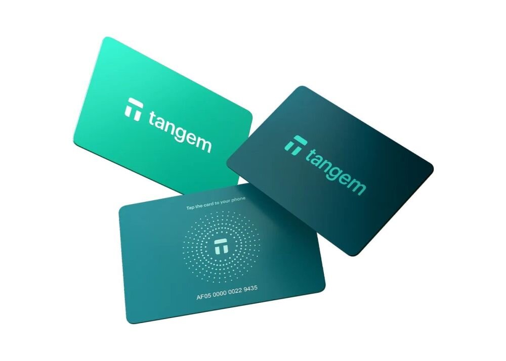 Pastelowe karty Tangem w kolorach fioletowym, różowym i turkusowym są ułożone wachlarzowo na białym tle - portfel kryptowalutowy w formie trzech kart 