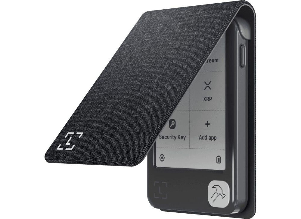 Etui LEDGER Nano Gen5 Magnet Folio pomarańczowy Portfel sprzętowy do kryptowalut w otwartym, ciemnym, teksturowanym etui z klapką. Etui jest czarne lub granatowe. Na ekranie widoczne opcje zarządzania walutami (np. Ethereum, XRP) i aplikacjami.