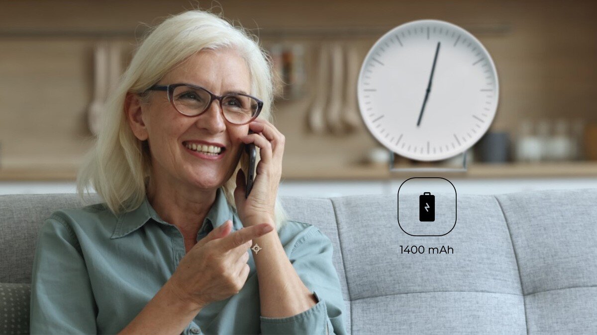 Uśmiechnięta kobieta w okularach rozmawia przez myPhone 7340 LTE na kanapie; w tle zegar; ikonka baterii 1400 mAh.