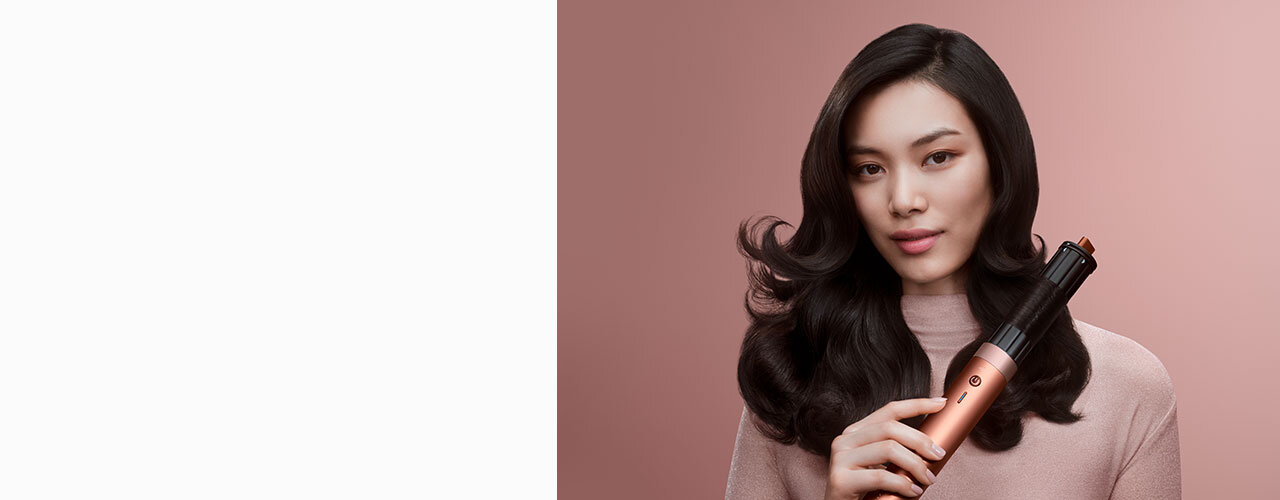 Modelka z ciemnymi włosami używa multistylera Dyson Airwrap Coanda2x do kręcenia loków.