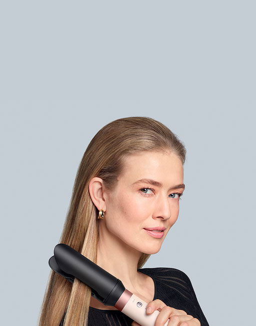 Modelka o blond włosach wygładza włosy używając multistylera Dyson Airwrap Coanda2x. Wersja mobile.