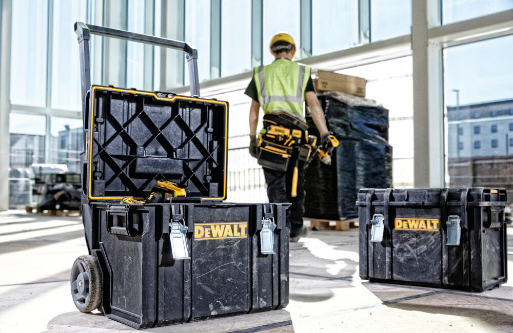 Skrzynka narzędziowa DEWALT DS450 pomieszczenie otwarta skrzynia obok druga skrzynia zamknięta w tle osoba okna wewnętrzne mocowanie modułu Tracer DEWALT Tracker śledzenie lokalizacji skrzyni przez system Tool Connect bezpieczeństwo sprzętu szybko odnaleźć skrzynię w przypadku zagubienia lub kradzieży