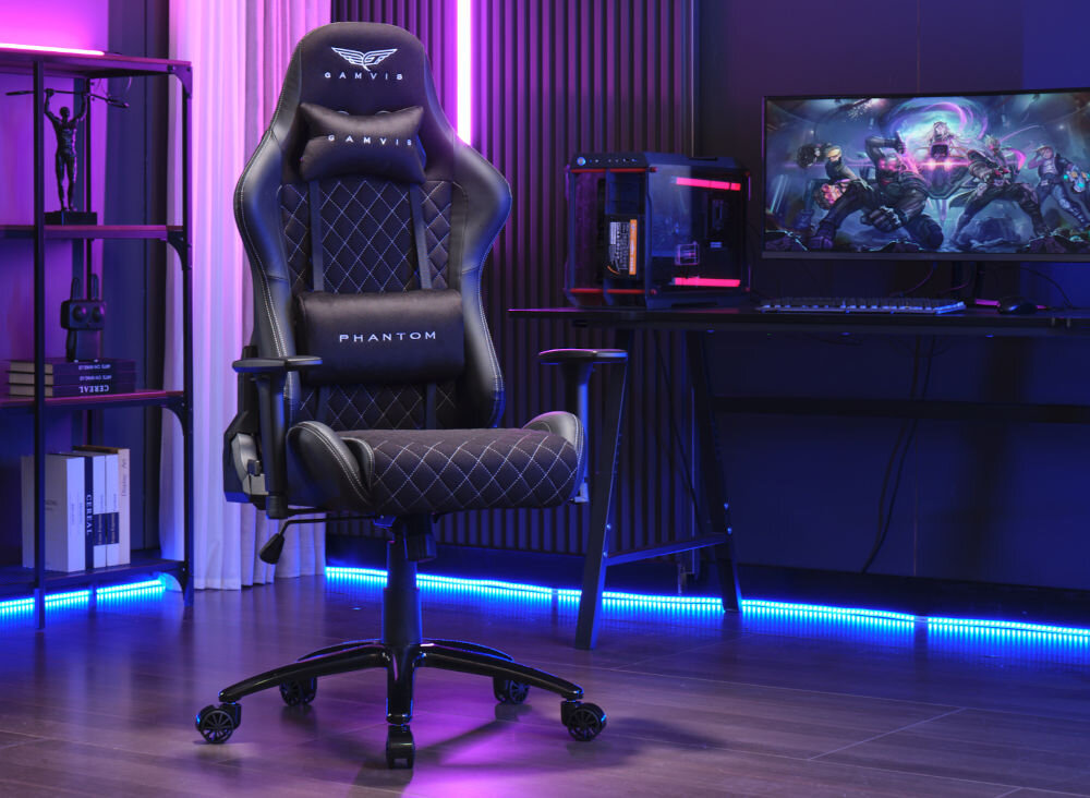 Fotel GAMVIS Phantom Large Czarny (białe elementy) prezentacja fotela od przodu pod kątem w ciemnym pokoju gamingowym na biurku monitor i komputer do 100 kg bezpieczne stabilne użytkowanie trwałość wygoda