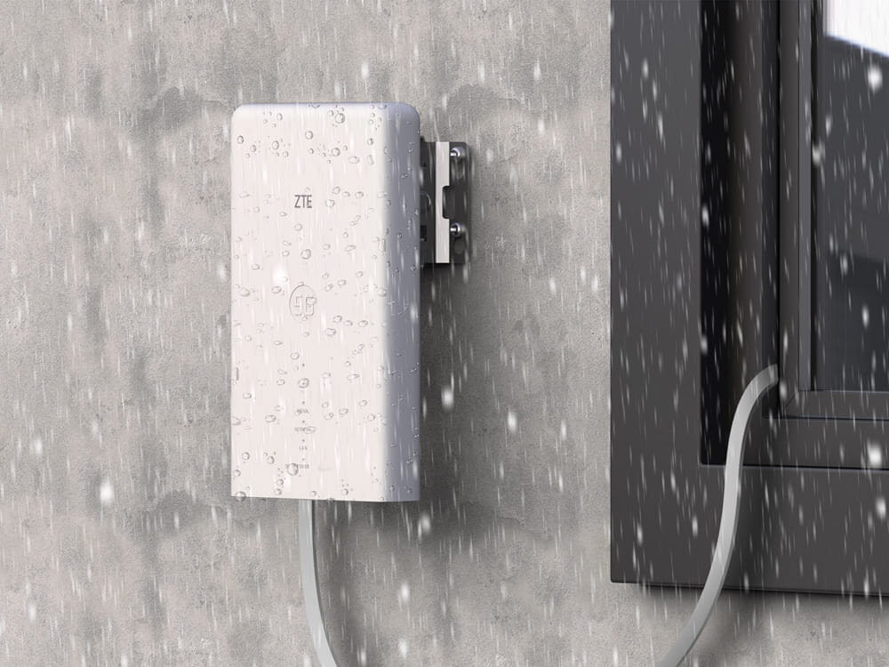 Router ZTE MC889 5G + Router ZTE T3000 IDU Białe urządzenie ZTE MC889 zamontowane na szarej ścianie, pokryte kroplami deszczu i podłączone kablem. Sprzęt jest odporny na pył i wodę, posiada klasę IP65 i pracuje w szerokim zakresie temperatur.