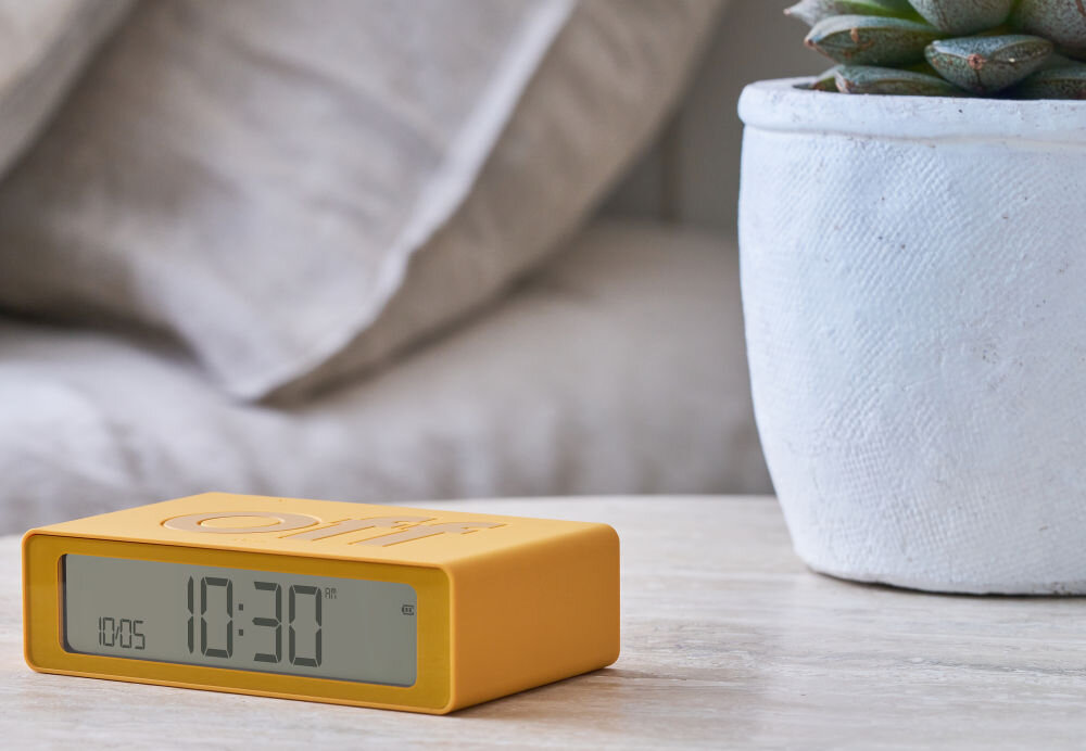 Budzik LEXON Flip Mini żółty, podróż, USB-C, bateria, ekran, Klasyczny Lexon Flip Mini z napisem „off”, matowa grafitowa obudowa, jasny blat, wyraźny ekran.