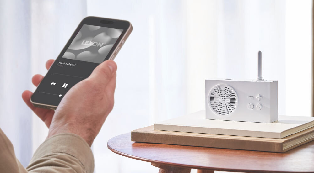 Radioodtwarzacz LEXON Tykho 3 biały, mobilność, ABS, panel, sterowanie, Smartfon z aplikacją muzyczną, radio Lexon Tykho 3 łączy się przez Bluetooth na tle jasnego okna.