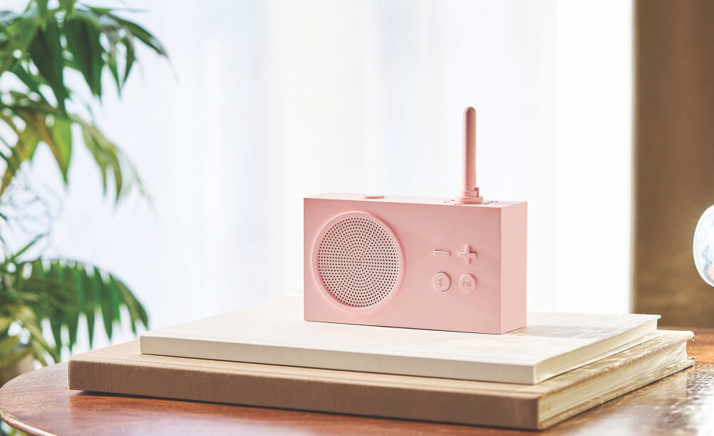 Radioodtwarzacz LEXON Tykho 3 różowy, radio, muzyka, funkcjonalność, Technologia,  Radio Lexon Tykho 3 stoi na jasnych książkach, roślina w tle, minimalistyczny wystrój.