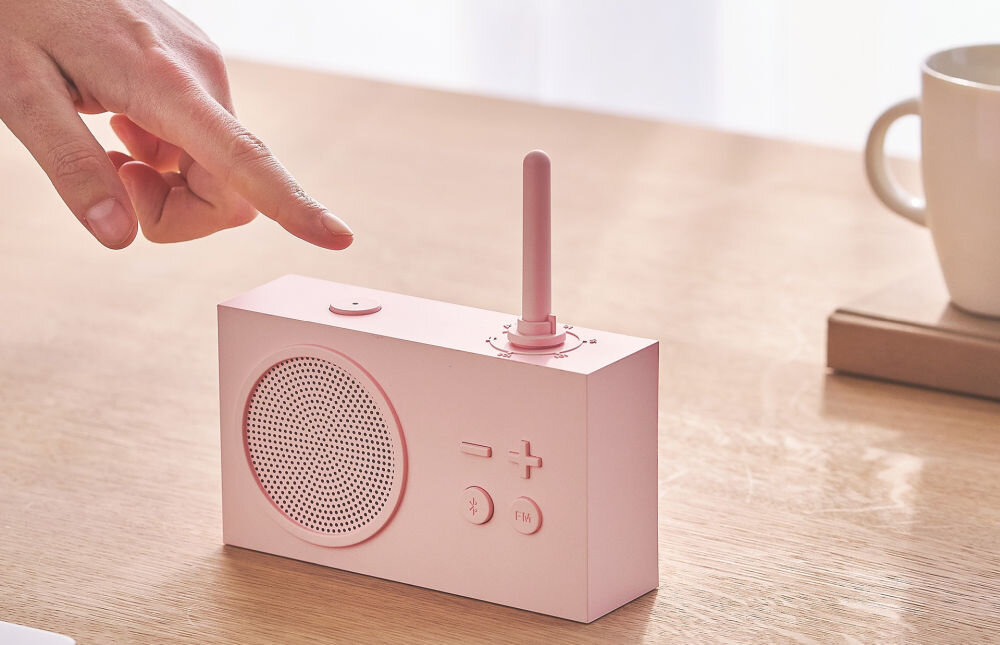 Radioodtwarzacz LEXON Tykho 3 różowy, design, matowe wykończenie, styl, minimalizm, Palec dotyka przycisku na radiu Lexon Tykho 3, panel z głośnikiem, filiżanka w tle.
