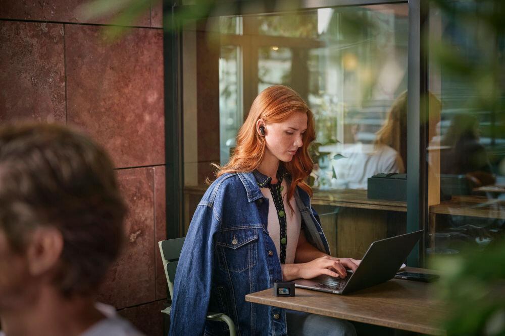 Słuchawki dokanałowe PHILIPS TAT6000BK/00 aplikacja personalizacja ustawienia niskie opóźnienie, osoba z założonymi słuchawkami pracująca przy laptopie