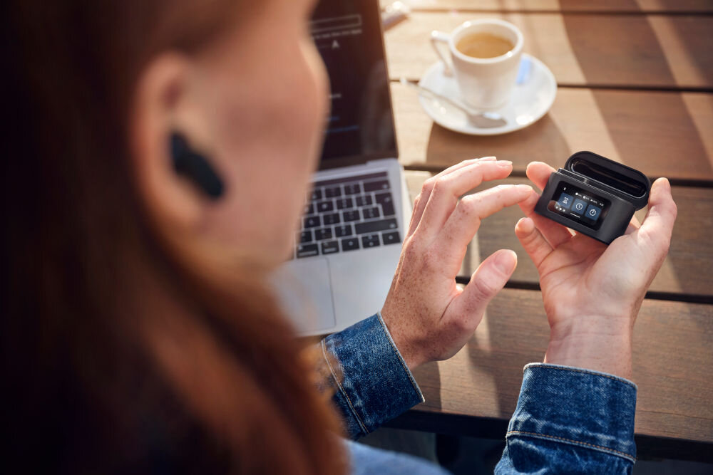 Słuchawki dokanałowe PHILIPS TAT6000BK/00 IPX5 wodoodporność silikonowe nakładki komfort użytkowania, osoba z założonymi słuchawkami trzymająca etui w ręku