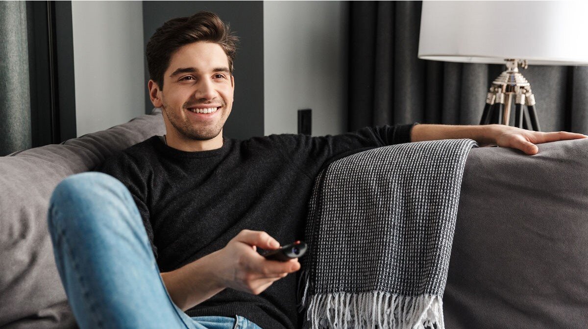 Soundbar SHARP HT-SBW55121 HDMI eARC CEC pilot sterowanie korektor tryby, osoba siedząca na kanapie z pilotem w ręku