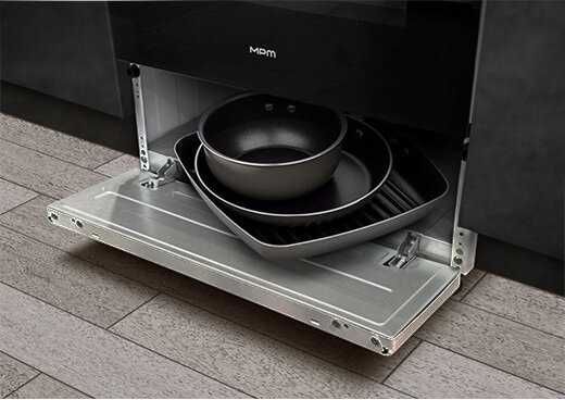 Otwarty schowek kuchenki elektrycznej z płytą ceramiczną MPM-55-KEC-40. W środku 2 patelnie i miseczka.