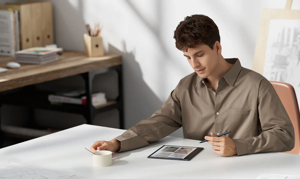 Czytnik e-booków ONYX BOOX Note Air 4 C 10.3 cala, Podświetlany ekran, Wi-Fi, Bez reklam Czarny prezentacja urządzenia podczas korzystania przez chłopaka siedzącym przy białym stole trzymający w dłoni rysik dla osób oczekujących sporej przestrzeni roboczej praca z dokumentami projekty graficzne materiały szkoleniowe swoboda tworzenia