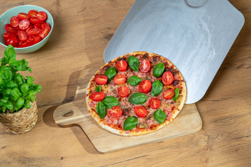 Piec do pizzy GÖTZE & JENSEN PO400K 1700W średnica 32 cm kamień do pieczenia i łopatka w zestawie Czarny piec na białym tle widoczny od przodu pod skosem ze stali nierdzewnej odporny na zarysowania profesjonalna łopatka do pizzy duża powierzchnia łopatki szybkie wygodne bezpieczne pizza jak z pizzerii