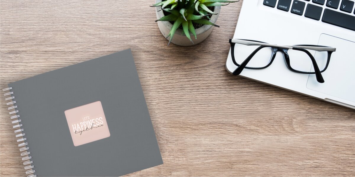 Album HAMA Fine Art 9838 Szary (50 stron) Kobieta nakładająca szminkę, korzystając z telefonu iPhone z zamontowaną białą lampą pierścieniową LED do selfie marki Hama.