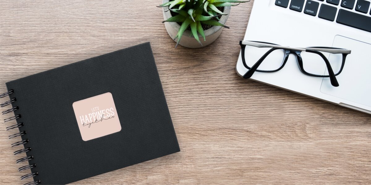 AAlbum HAMA Fine Art 9833 Czarne kartki Czarny (50 stron) Album fotograficzny Let's Happiness Together na drewnianym biurku obok laptopa, okularów i rośliny.