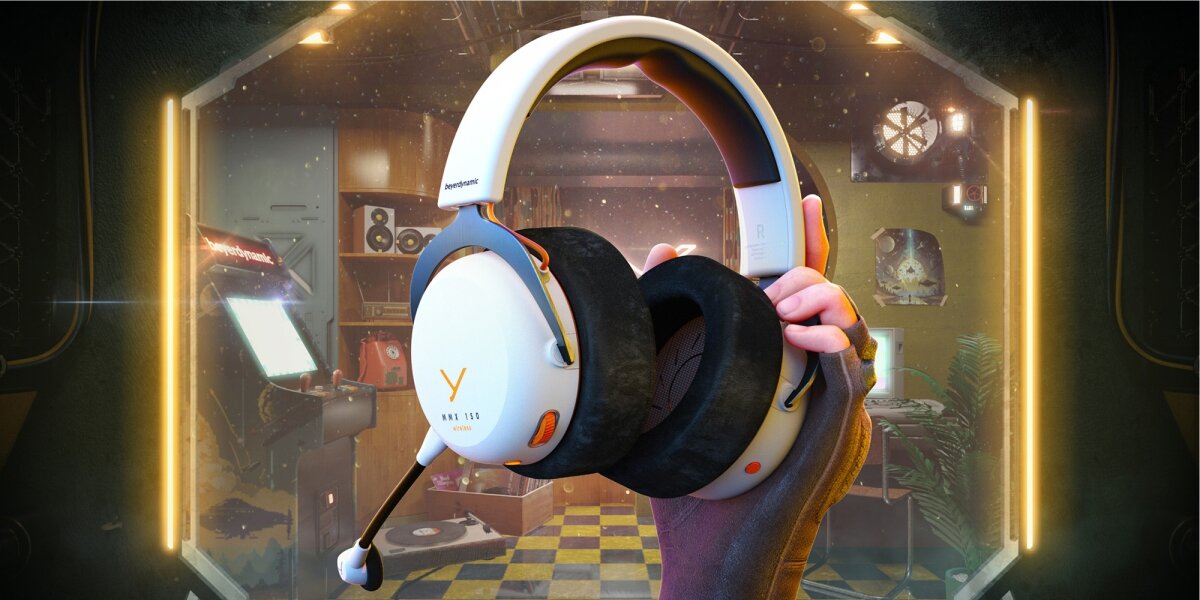 Słuchawki gamingowe beyerdynamic MMX 150 Wireless (białe z pomarańczowymi akcentami) trzymane w dłoni, z widocznymi dużymi, welurowymi nausznikami i mikrofonem. Tło to stylizowany pokój gracza z automatami do gier i neonami.