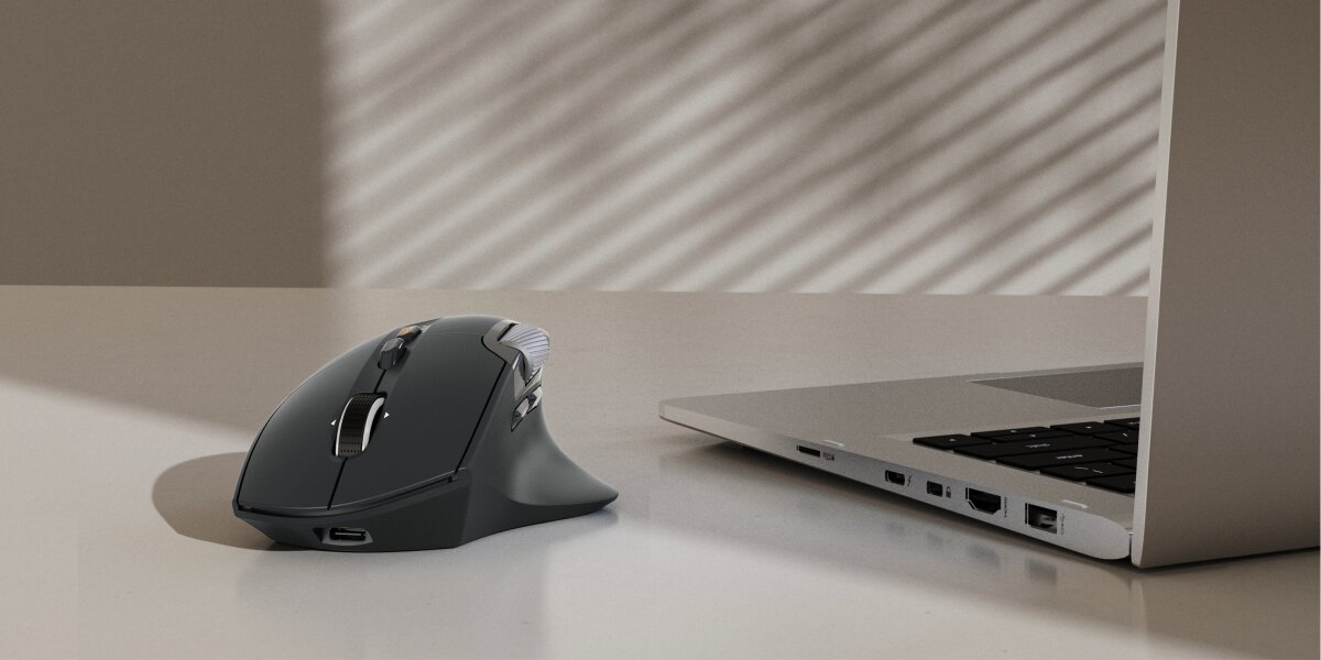 Mysz HAMA WM-900 Czarny Czarna ergonomiczna mysz bezprzewodowa Hama leżąca na biurku obok laptopa w nowoczesnym biurze.