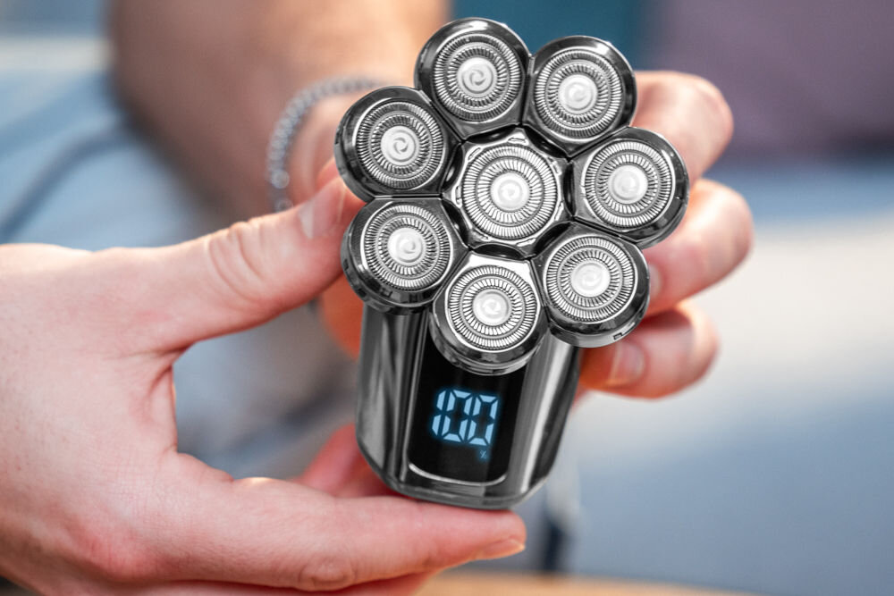 Golarka do głowy GÖTZE & JENSEN MS503 ze zdjętą osłoną trzymaną w dłoni z aktywnym wyświetlaczem ze stanem naładowania