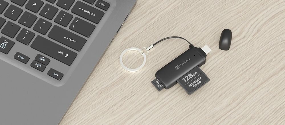 Czytnik kart pamięci NATEC Scarab C USB 3.2 Czarny Czytnik kart z breloczkiem i kartą pamięci, umieszczony w pobliżu laptopa na drewnianej powierzchni